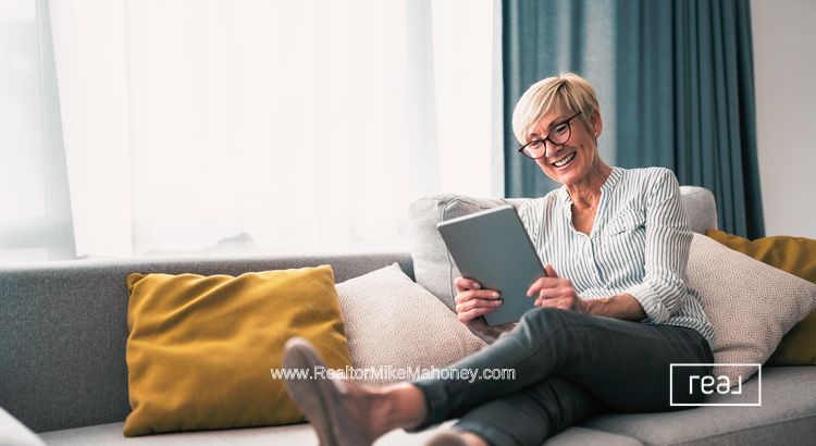 Woman on a couch reading real estate news on her ipad